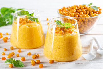 Two glasses of healthy vitamin sea buckthorn Mousse on a white wooden background.