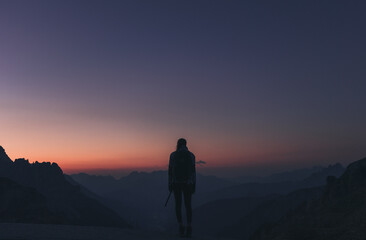 Fototapeta na wymiar Silhouette einer jungen Frau vor einer Gebirgskette zu Sonnenaufgang