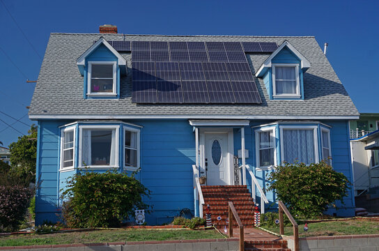 San Pedro, California USA - July 2, 2021: Solar panels on the roof of a vintage, traditional bungalow style house beneath a blue summer sky in the Los Angeles suburb.