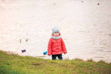 Children play with boats on the river bank. sunny autumn. yellow park. blue river at sunset