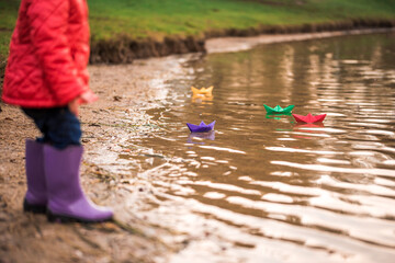 Children play with boats on the river bank. sunny autumn. yellow park. blue river at sunset
