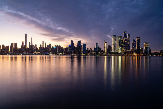 New York, NY - USA - Horizontal image of the skyline of the westside of Manhattan at sunrise, with reflections seen in the Hudson River.