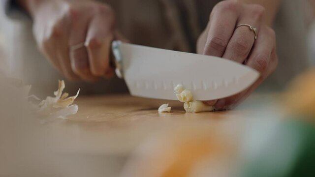 close up hands chopping garlic cloves using knife preparing fresh homemade meal with vegetables for cooking healthy organic lifestyle at home 4k footage