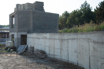 Construction site. The walls of the house being built. Next to it is a retaining wall filled with...