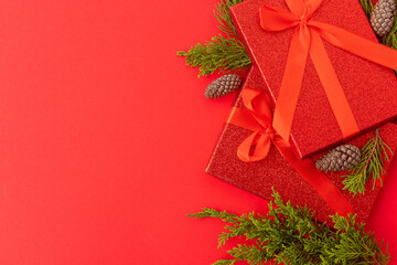 A very beautiful Christmas arrangement of gifts. coniferous branches and cones on a red background. High angle view. Christmas, New Year. banner. poster, postcard.
