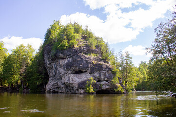 Fototapeta na wymiar Tree topped rock cliff at water's edge