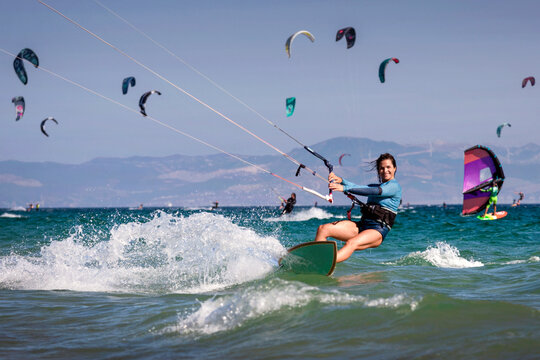 Smiling woman kitesurfing in ocean with other kitesurfer, Tarifa beach, Cadiz, Andalusia, Spain