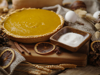 Traditional American pumpkin pie, ingredients, decor. A festive dish. Restaurant, hotel, cafe, advertising. Close-up. Careful viewing. Pastel shades. There are no people in the photo.