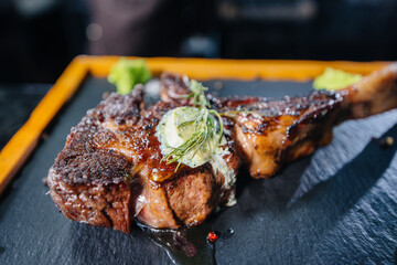 Close-up of a beautifully grilled juicy steak with butter and seasonings. Grilled meat in a...