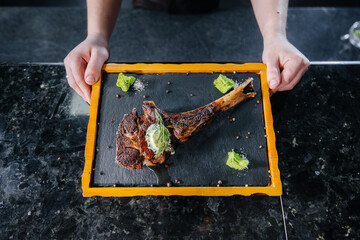 A professional chef beautifully serves a juicy grilled steak with butter and seasonings. Grilled...
