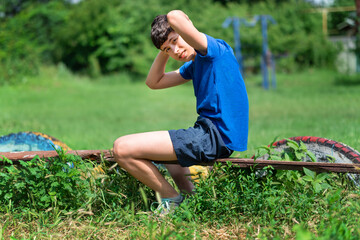 teenage boy exercising outdoors, sports ground in the yard, he pumps his abs on the board on the...