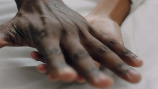 close up young mixed race couple holding hands lying in bed together enjoying playful romantic relationship 4k footage