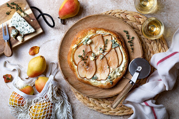 Pizza with pear, thyme, ricotta and blue cheese on  wooden board and wine glasses