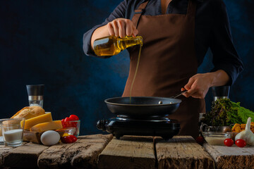 The cook pours olive oil into a frying pan. He prepares the classic Caesar salad from the ingredients on the table. Close-up. Step by step recipe, recipe book, culinary blog.