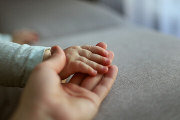 The mother's hands holding the babys small hand