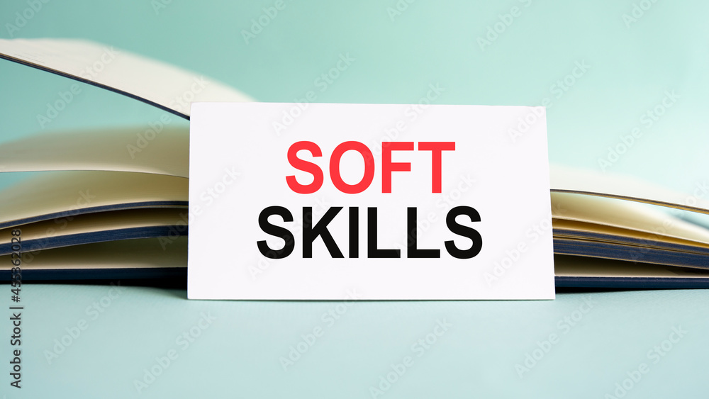 Aufkleber a white business card with soft skills text stands on a desk against the background of an open diary