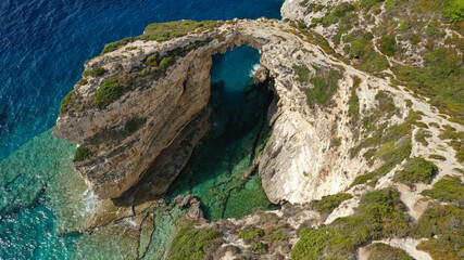 Aerial drone photo of scenic rock formation and natural arch of Tripitos over turquoise crystal clear Ionian sea, Paxos island, Greece