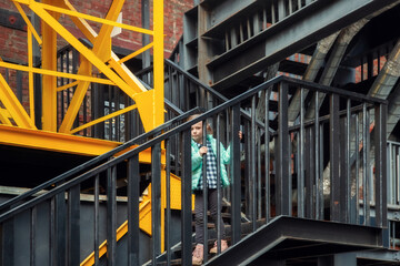 Fototapeta premium Little caucasian blonde girl in fashionable clothes descends the metal steps