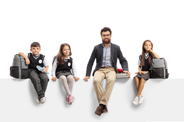 Fototapeta premium Schoolchildren and a male teacher with books sitting on a blank panel