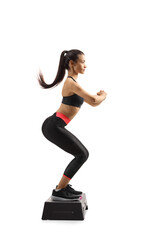 Full length profile shot of a young woman exercising step aerobic
