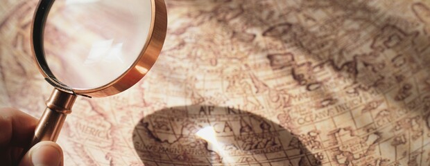 Retro copper colored magnifying glass and old white nautical chart close-up. Vintage still life....