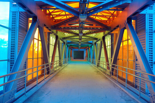 A futuristic pedestrian overpass over a motorway made from a glass steel overpass.