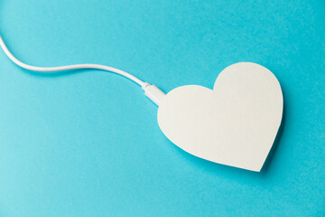 The power bank is connected to the heart on blue background. The concept of a healthy lifestyle....
