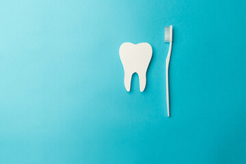 The concept of the International Day of the Dentist. A white toothbrush and a paper tooth on a blue...