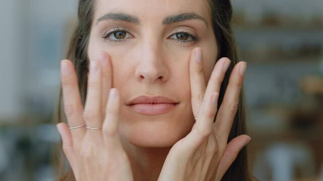portrait attractive young woman looking in mirror at perfect healthy skin touching face with hands enjoying smooth natural complexion with anti aging skincare getting ready at home beauty concept