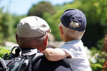 grandpa and grandson looking into the nature with hats on their heads