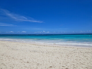 Fototapeta na wymiar Photo of waves lapping empty Caribbean beach under bright blue sky.