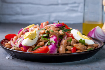 Salad of white beans, tomatoes and onions, boiled eggs, Classic Turkish cuisine. Side view.