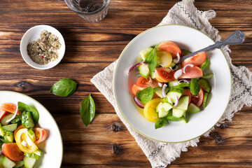 Fresh green salad in white bowl on wooden table. Rustic style.