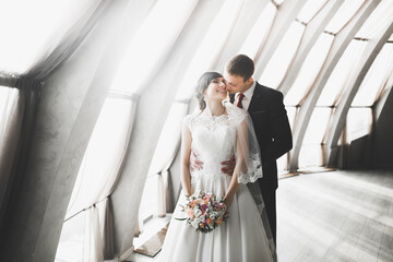 Lovely happy wedding couple, bride with long white dress posing in beautiful city