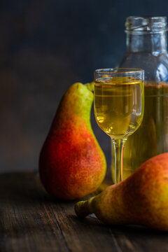 Fresh pears on a table next to a glass and bottle of traditional Georgian chacha brandy
