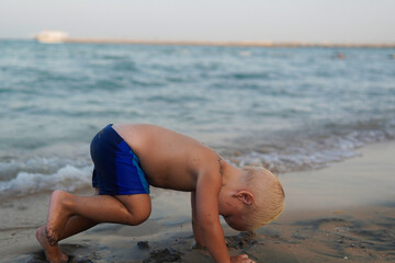 little boy with blonde hair having fun on the beach