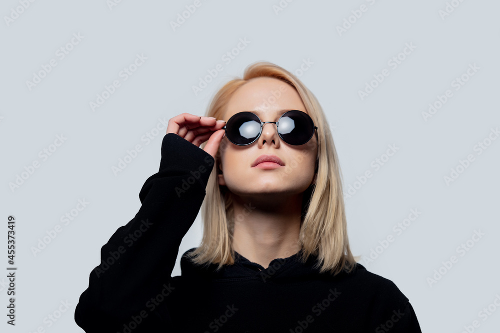 Wall mural blonde in black and round sunglasses on a white background