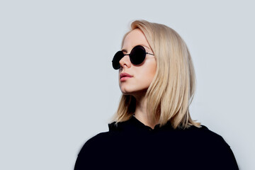 blonde in black and round sunglasses on a white background