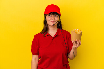 Young curvy caucasian woman fast food restaurant worker holding fries isolated on blue background...