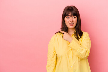 Young curvy caucasian woman isolated on pink background pointing to the side