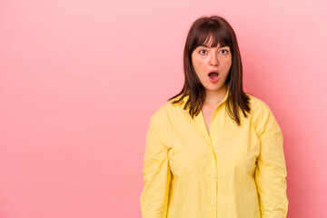 Young curvy caucasian woman isolated on pink background being shocked because of something she has seen.