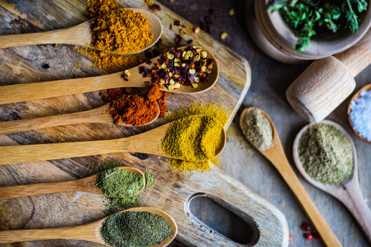 Wooden spoons on a chopping board filled with assorted dried spices and seasoning