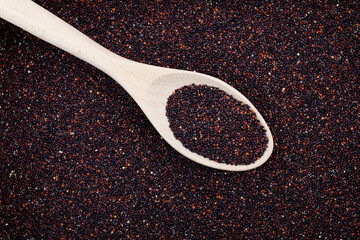 Organic black quinoa or ragi in wooden spoon, top view. Natural cereal background, selective focus, copy space. Design element