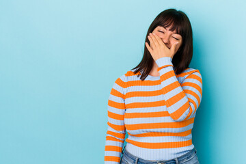 Young curvy caucasian woman isolated on blue background laughing happy, carefree, natural emotion.