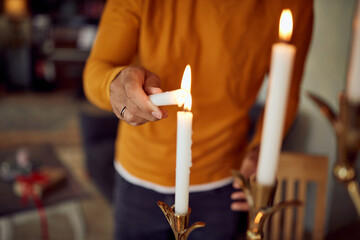 Close-up of Jewish man lights traditional candles during festival of lights, Hanukkah at home.
