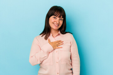 Young curvy caucasian woman isolated on blue background laughs out loudly keeping hand on chest.