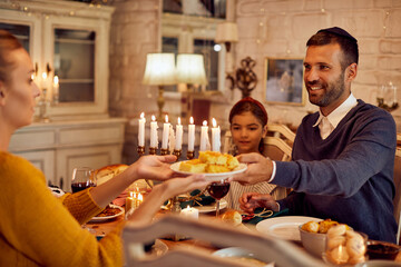 Happy Jewish family having traditional Hanukkah meal at home.
