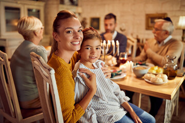 Happy Jewish mother and daughter enjoy during family meal on Hanukkah at home.