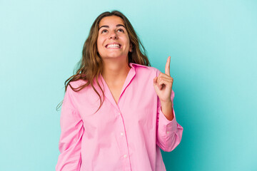 Young caucasian woman isolated on blue background  indicates with both fore fingers up showing a...