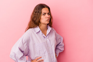 Young caucasian woman isolated on pink background  frowning face in displeasure, keeps arms folded.